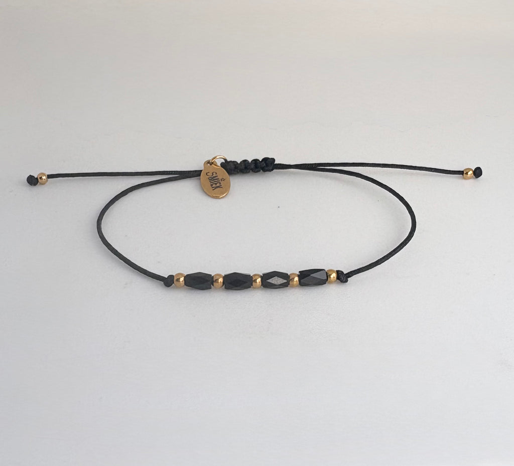 Armbandje met zwarte facet kraaltjes en stainless steel gouden details.